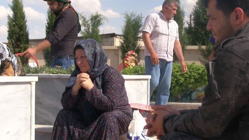 A mother cries next to her son’s grave in Rojava